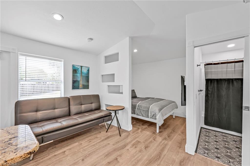 Living area with vaulted ceiling, recessed lighting, and light wood-style flooring