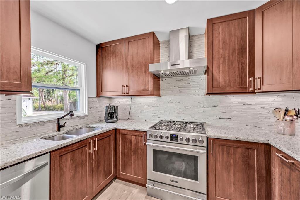 Kitchen with stainless steel appliances, wood finish cabinets, light stone counters, and decorative backsplash