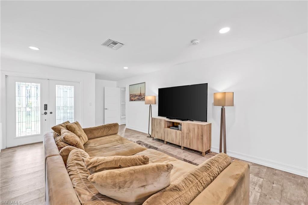 Living room featuring light wood-style flooring, recessed lighting, and french doors