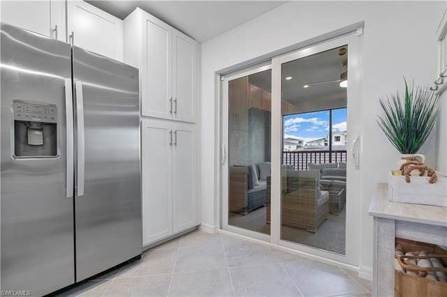 Kitchen with white cabinets, light tile patterned flooring, and stainless steel fridge