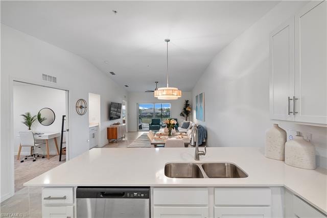 Kitchen with dishwasher, vaulted ceiling, sink, white cabinetry, and kitchen peninsula