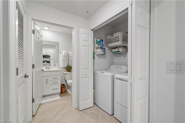 Laundry area featuring light tile patterned flooring and washer and clothes dryer
