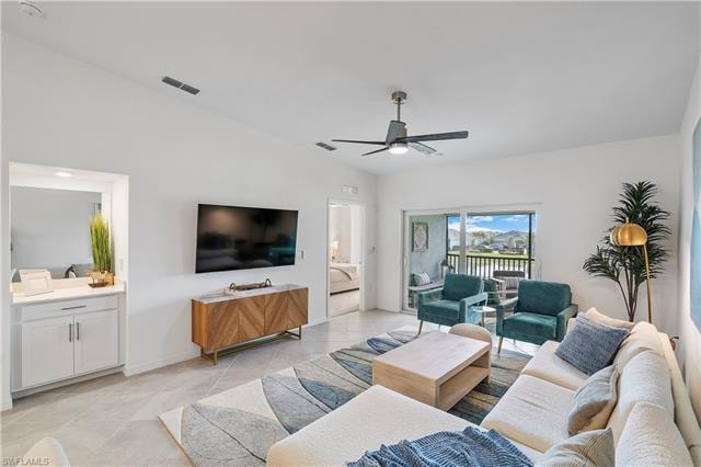 Living room featuring lofted ceiling, ceiling fan, and light tile patterned floors