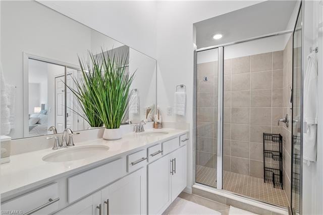 Bathroom featuring tile patterned flooring, vanity, and a shower with door