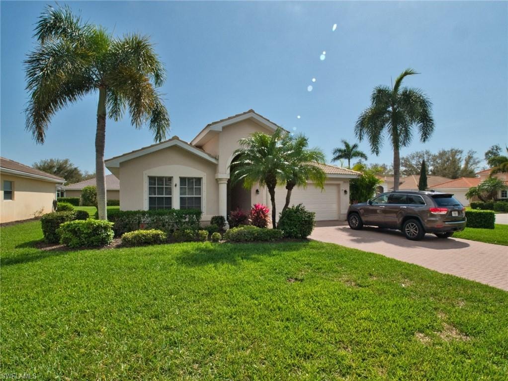 View of front facade with decorative driveway, an attached garage, a front yard, and stucco siding