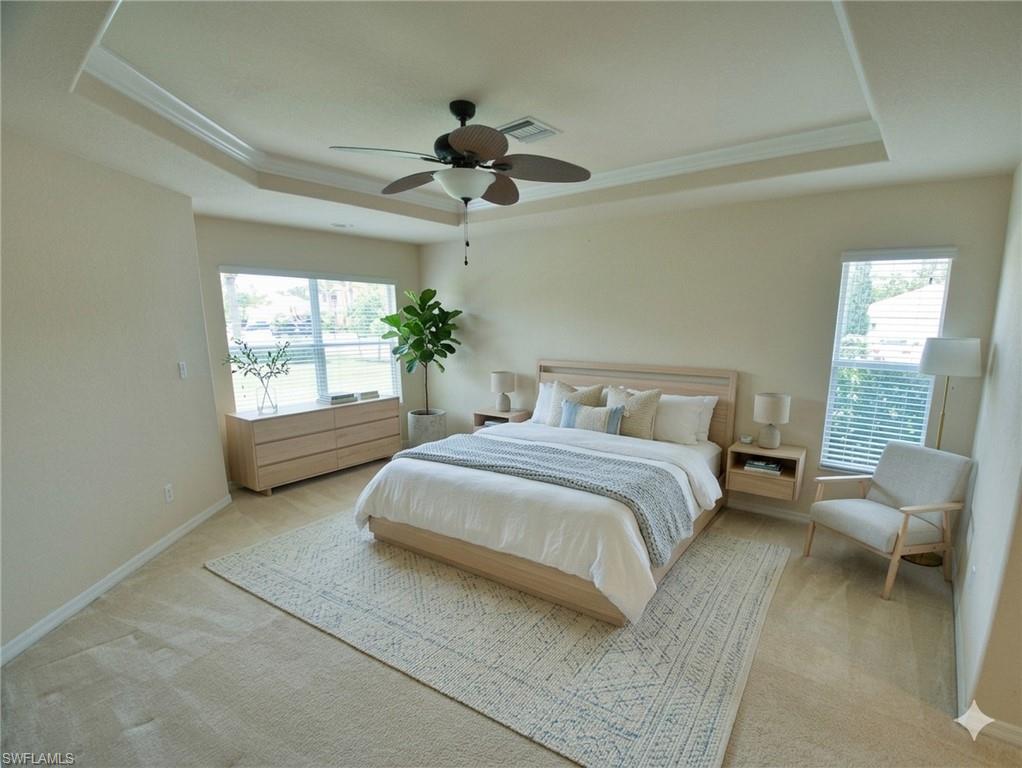 Spacious room featuring a tray ceiling with crown molding and a ceiling fan