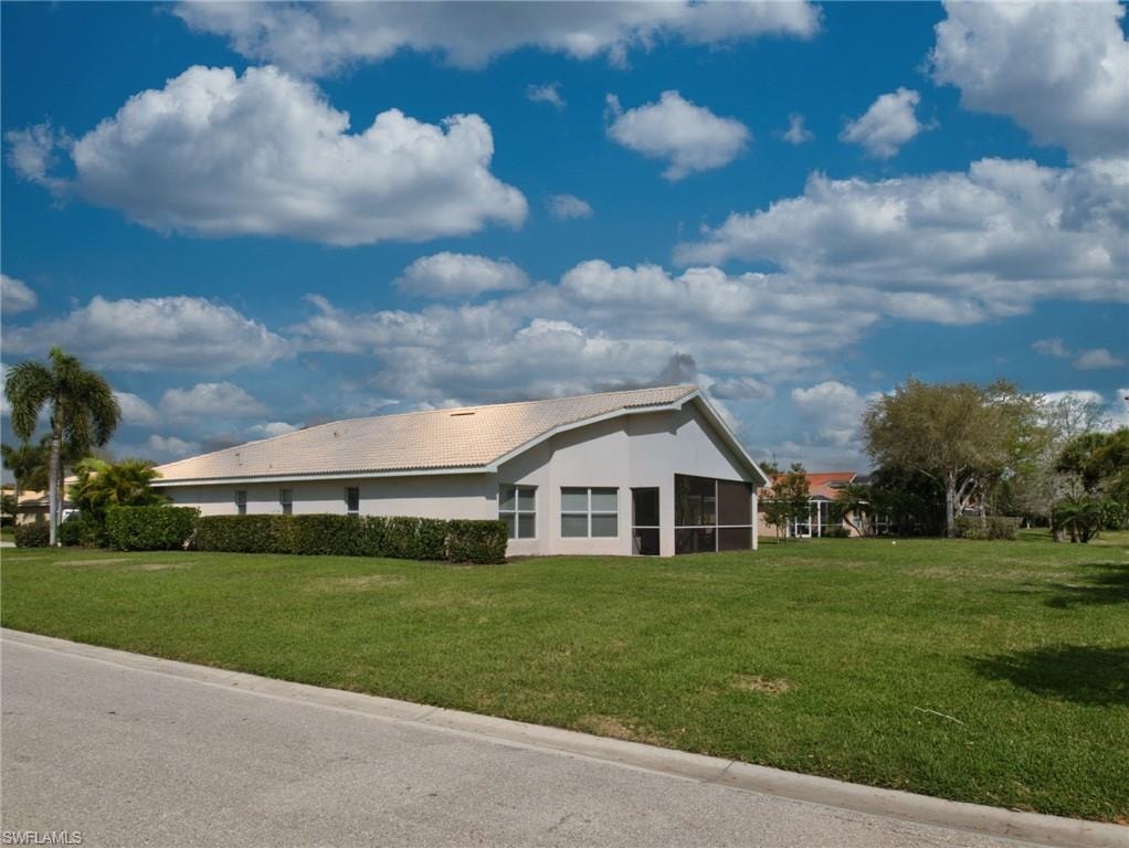 View of home's exterior with a lawn, stucco siding, a tiled roof, and a sunroom