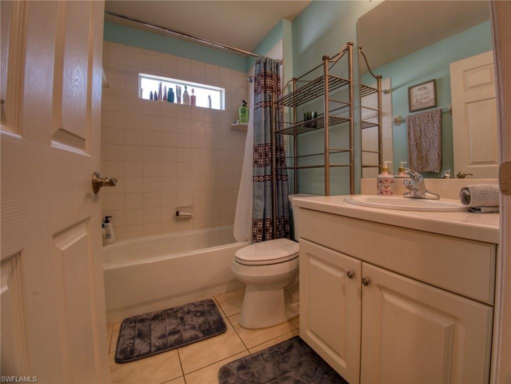 Bathroom with vanity, shower / tub combo, and light tile patterned floors