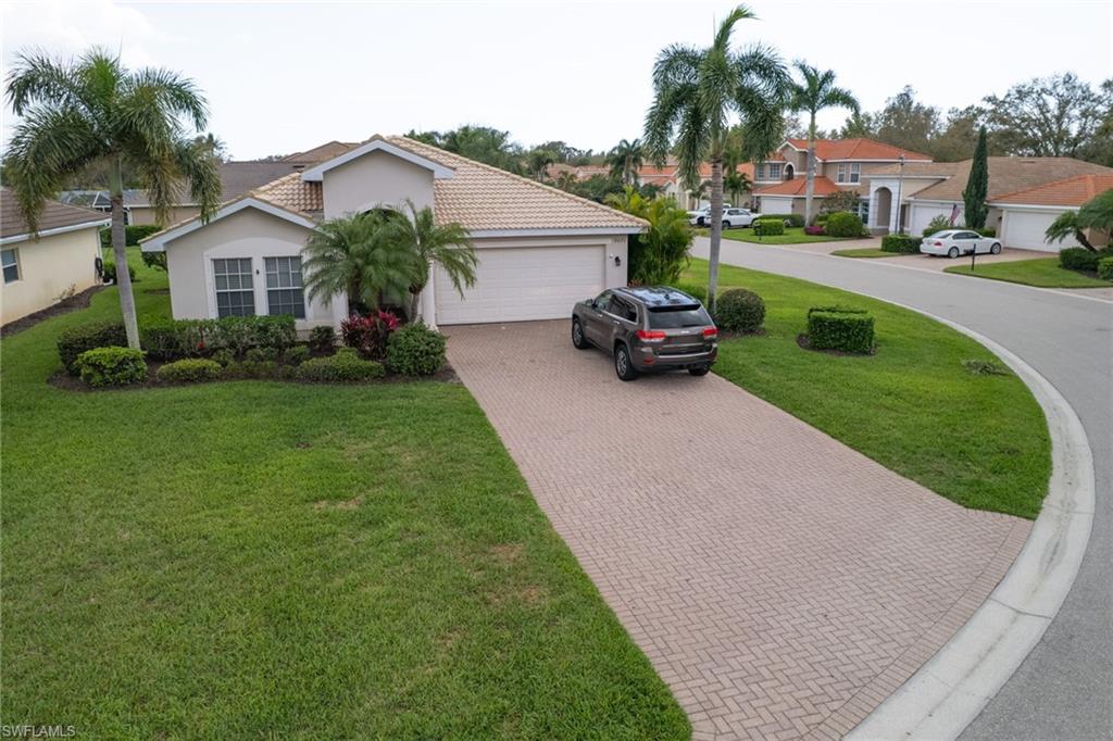 Mediterranean / spanish-style house with decorative driveway, a front lawn, an attached garage, stucco siding, and a residential view