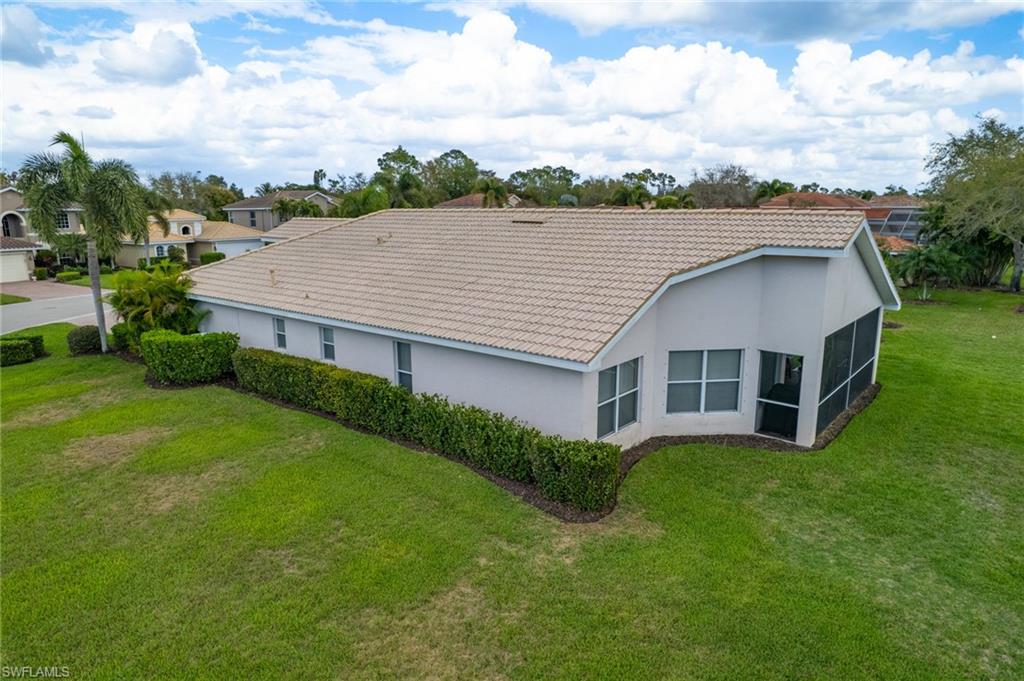 Back of property featuring a tiled roof, stucco siding, a yard, and a sunroom