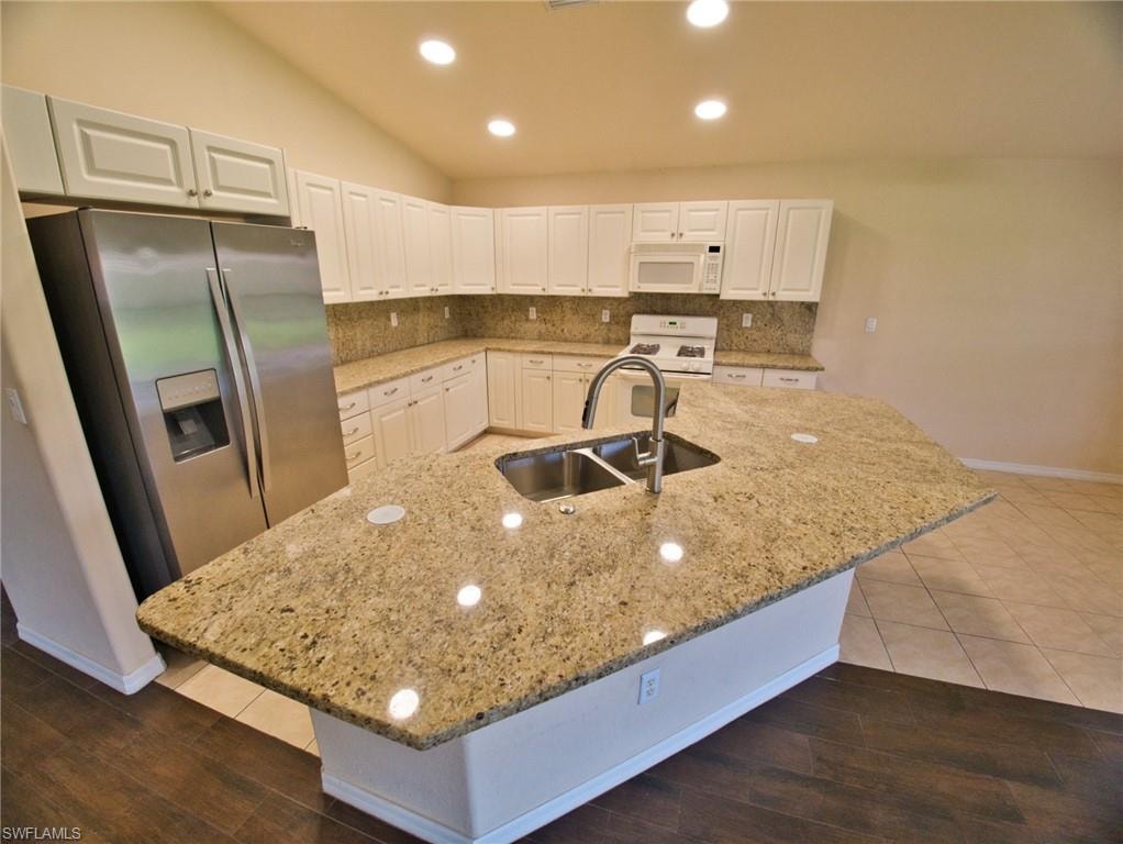 Kitchen featuring a large central island with a double basin sink and gooseneck faucet