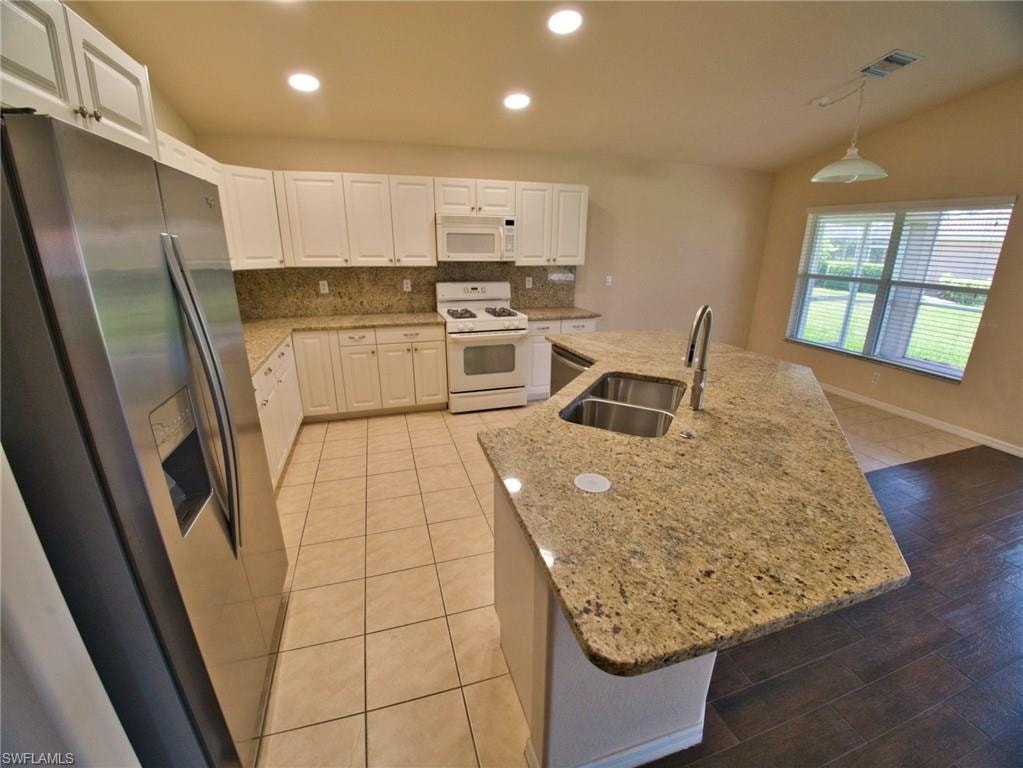 Kitchen featuring a large central island with a double stainless steel sink and a gooseneck faucet