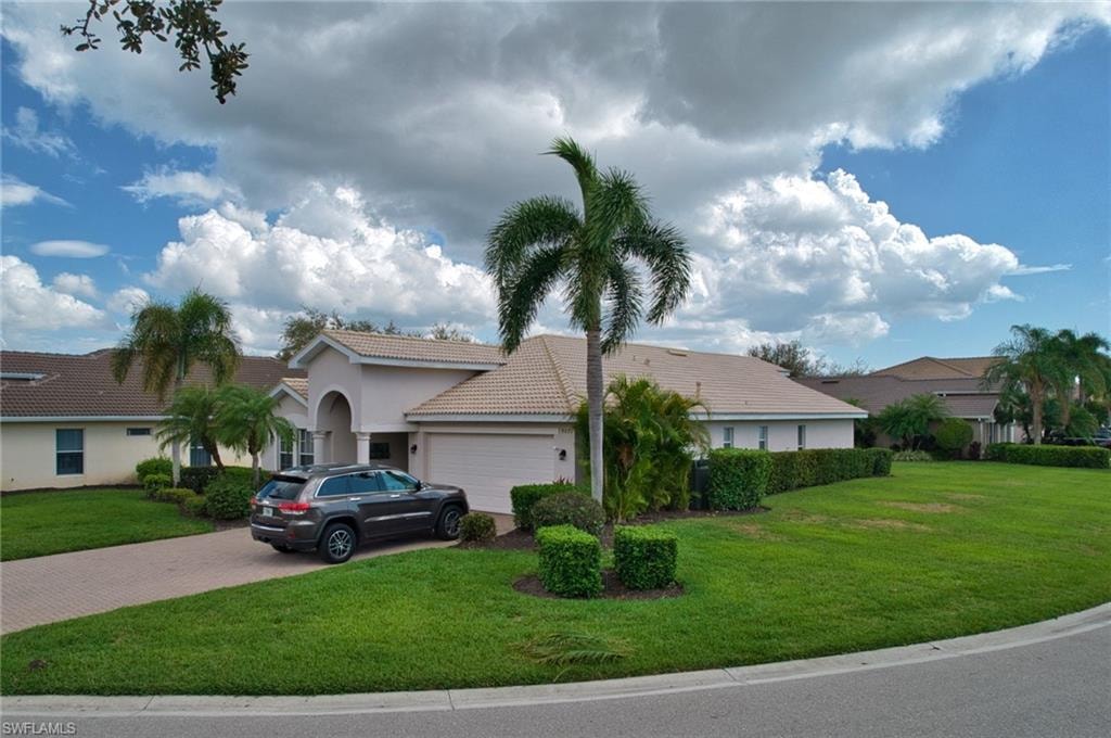 View of front of property with a front lawn, a tiled roof, an attached garage, decorative driveway, and stucco siding