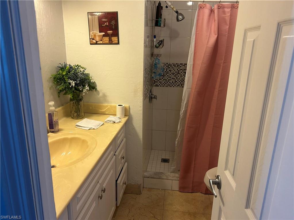 Full bath with vanity, a stall shower, and a textured wall