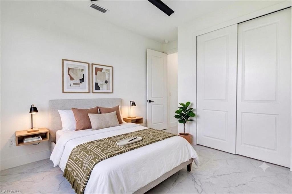 Unfurnished bedroom with light marble finish floors, a ceiling fan, and a closet