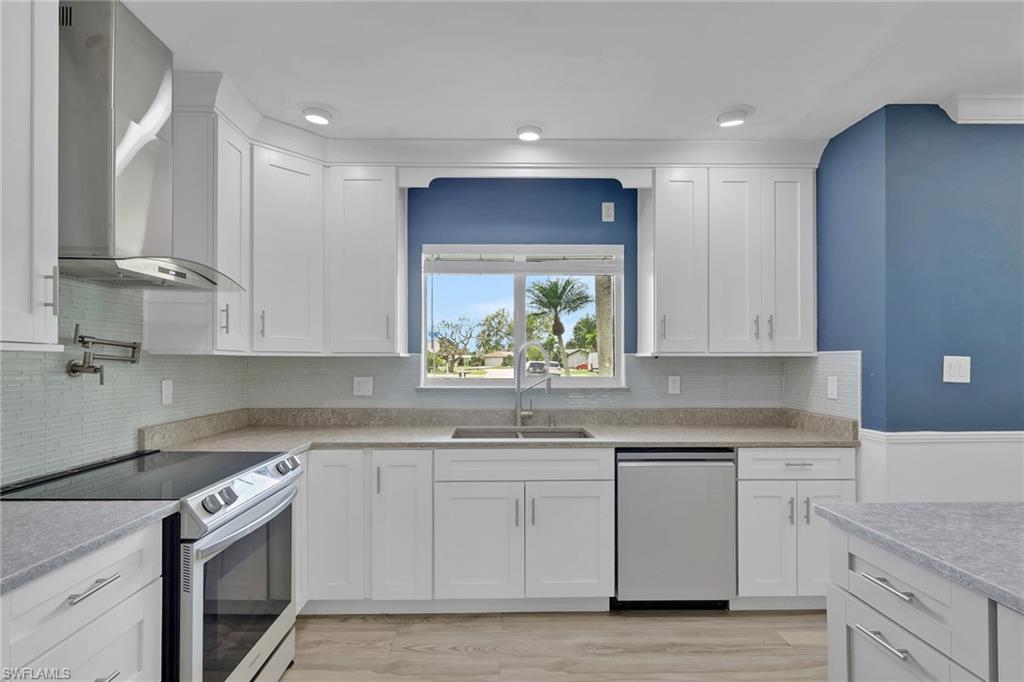 Kitchen featuring stainless steel appliances, white cabinetry, light wood-type flooring, and tasteful backsplash