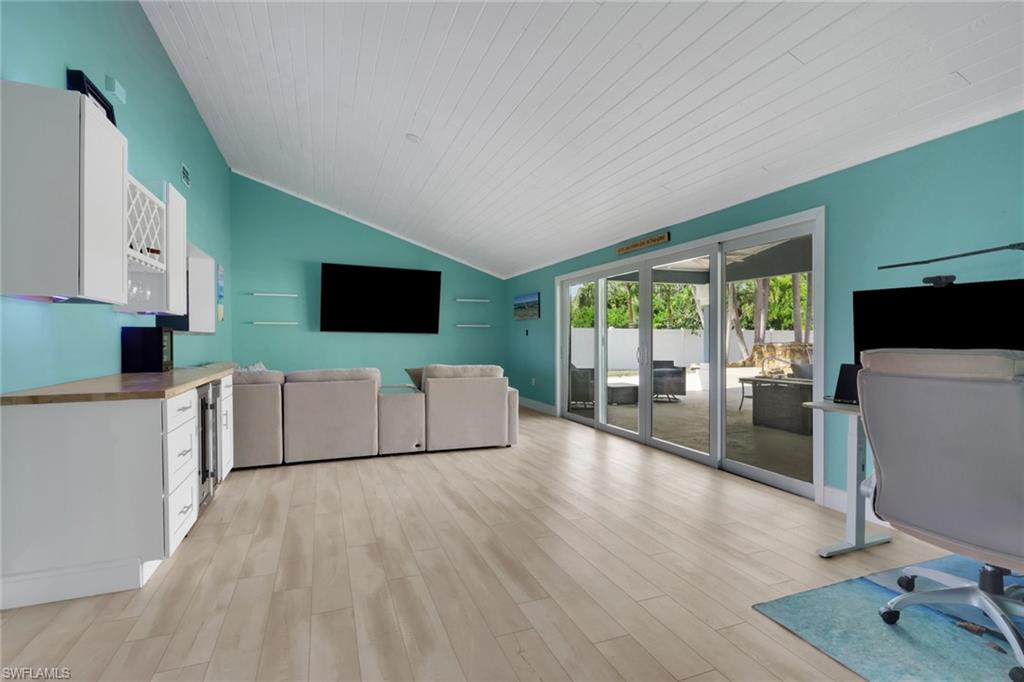 Living area featuring an office area, light wood-style flooring, a vaulted wood ceiling, and beverage cooler
