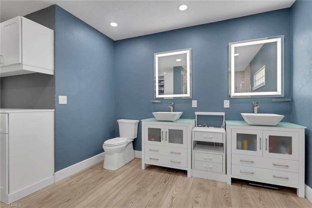 Bathroom featuring two vanities, light wood-style floors, and recessed lighting