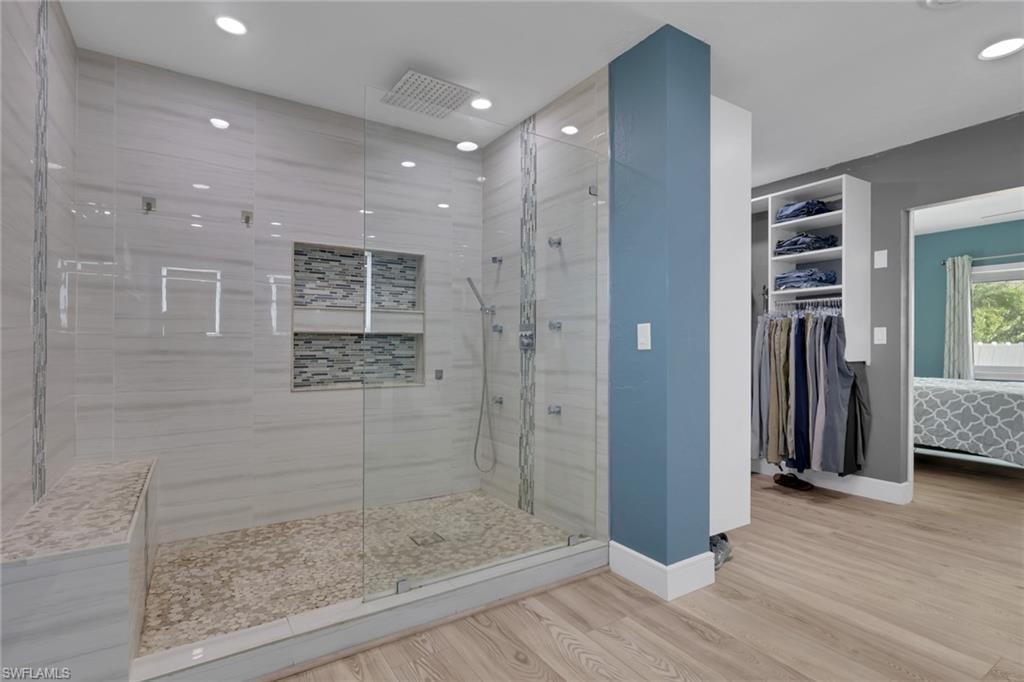 Full bathroom featuring ensuite bath, a stall shower, light wood-style floors, a spacious closet, and recessed lighting