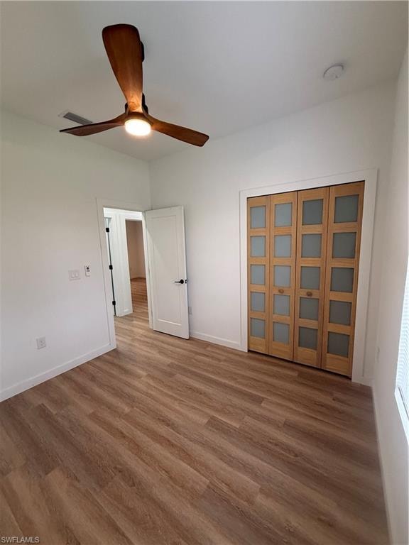 Unfurnished bedroom with wood finished floors, a ceiling fan, and a closet