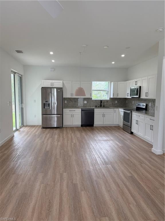 Kitchen with decorative backsplash, white cabinetry, refrigerator, and stove