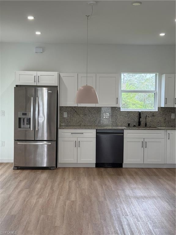 Kitchen with white cabinetry, backsplash, light stone countertops, and refrigerator