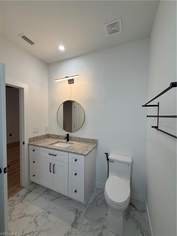 Half bathroom featuring vanity, light marble finish flooring, and recessed lighting