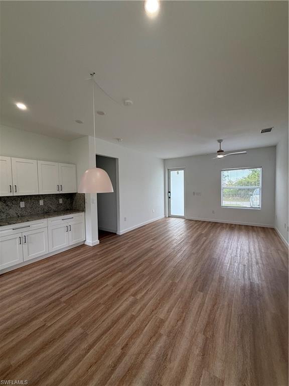 Unfurnished living room featuring dark wood-style floors, ceiling fan, and recessed lighting