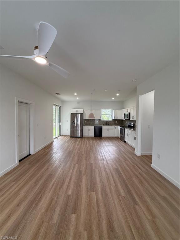 Unfurnished living room with light wood-type flooring, plenty of natural light, ceiling fan, and recessed lighting