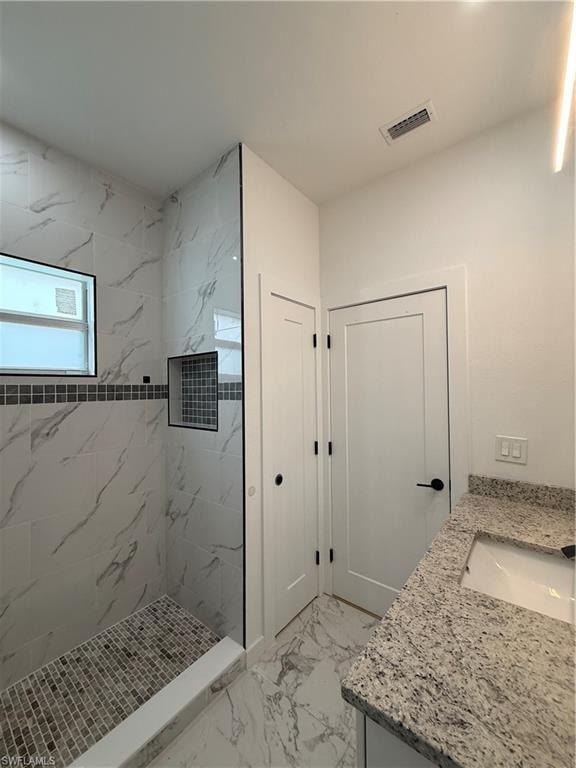 Full bath with vanity, a marble finish shower, and light marble finish flooring
