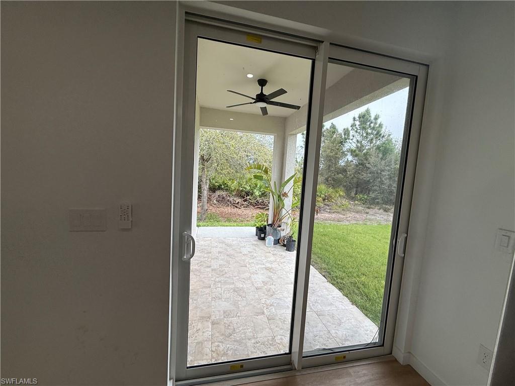 Doorway to outside with ceiling fan and baseboards
