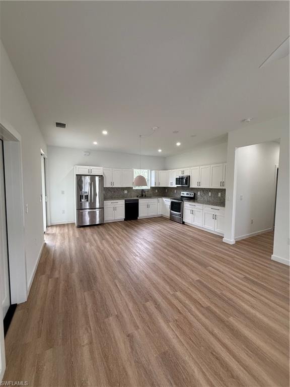 Kitchen featuring backsplash, white cabinets, range, and refrigerator