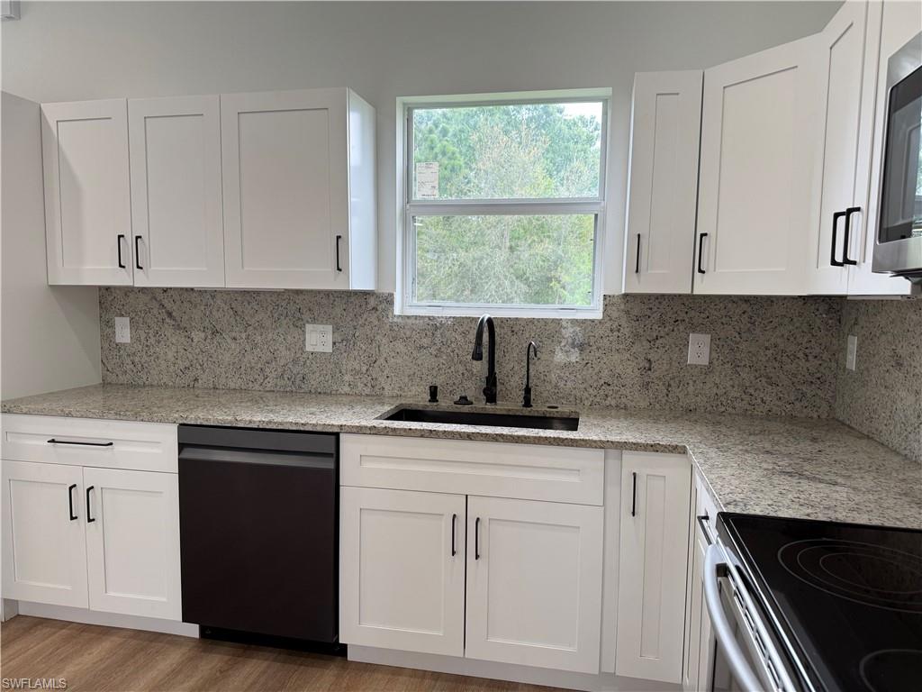 Kitchen featuring light stone countertops and white cabinetry