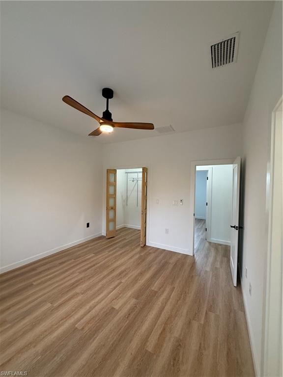 Unfurnished bedroom featuring light wood-style flooring, a ceiling fan, and a spacious closet
