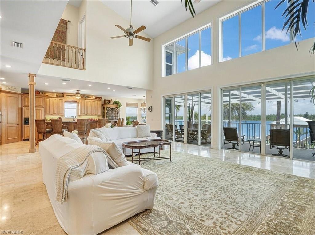 Living area with a ceiling fan, a high ceiling, and recessed lighting - Virtually Edited Image