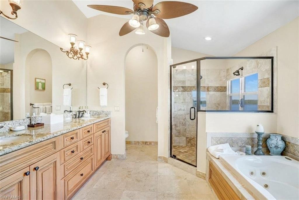 Bathroom with double vanity, a stall shower, a whirlpool tub, a ceiling fan, and light tile patterned flooring - Virtually Edited Image