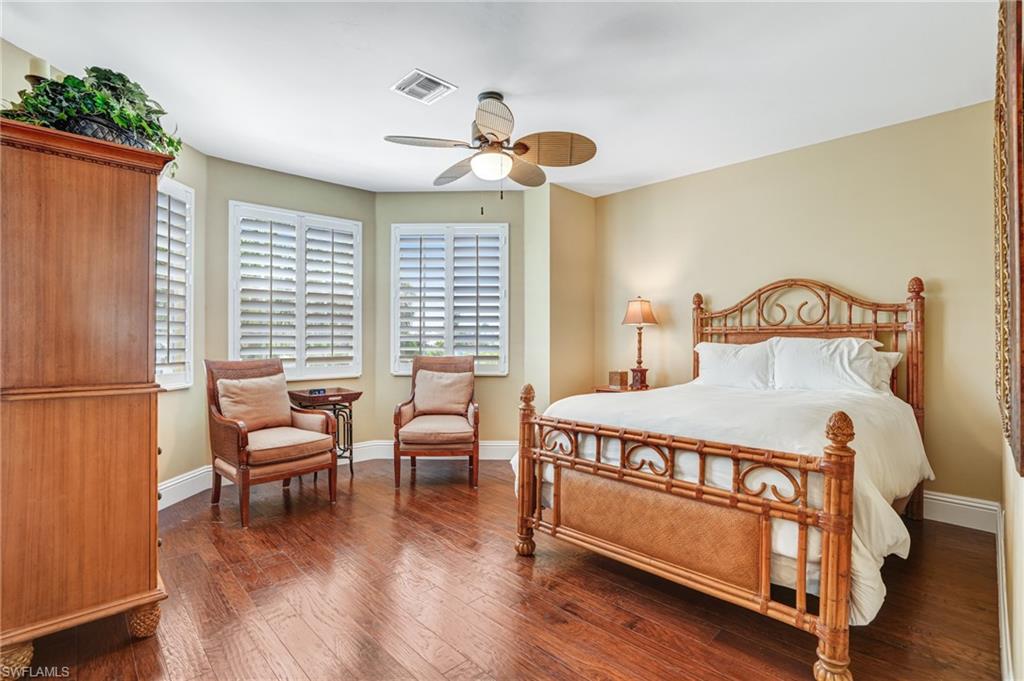 Bedroom with dark wood-style floors and a ceiling fan - Virtually Edited Image