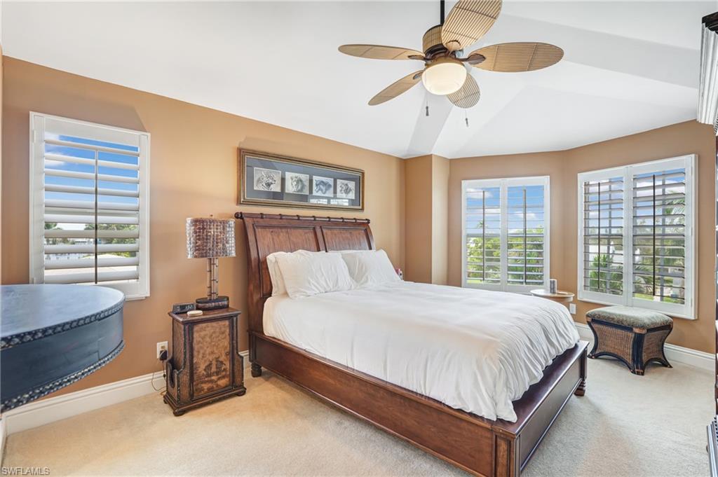 Bedroom featuring ceiling fan, carpet flooring, and multiple windows - Virtually Edited Image