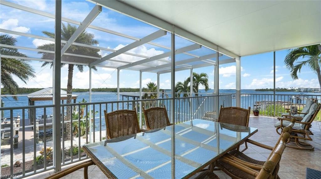 Sunroom with expansive windows, a water view, and tile patterned floors - Virtually Edited Image