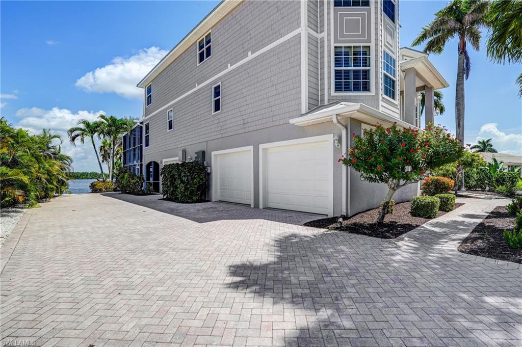 View of side of home featuring an attached garage and decorative driveway - Virtually Edited Image