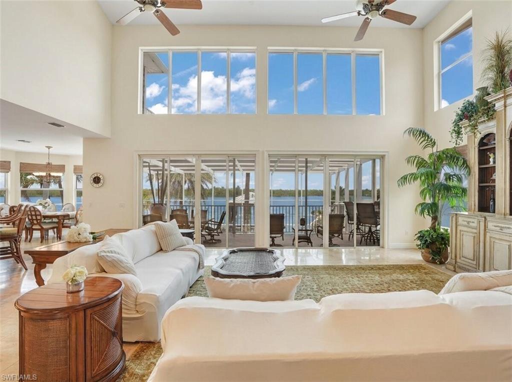Living room with a ceiling fan, a water view, a high ceiling, and suspended lighting - Virtually Edited Image