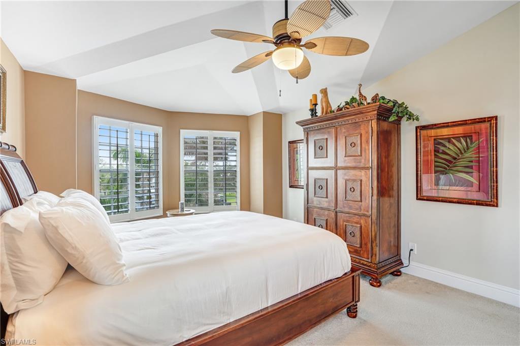 Bedroom with light colored carpet, ceiling fan, and vaulted ceiling - Virtually Edited Image