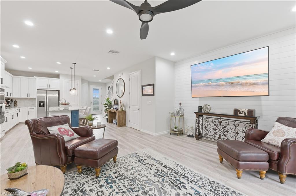 Living room with a ceiling fan, light wood-style flooring, recessed lighting, and wood walls