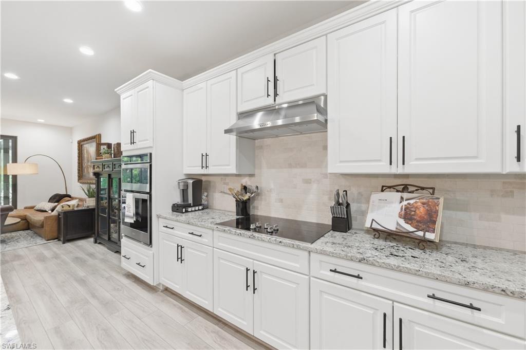 Kitchen with white cabinets, light stone counters, recessed lighting, and light wood-type flooring
