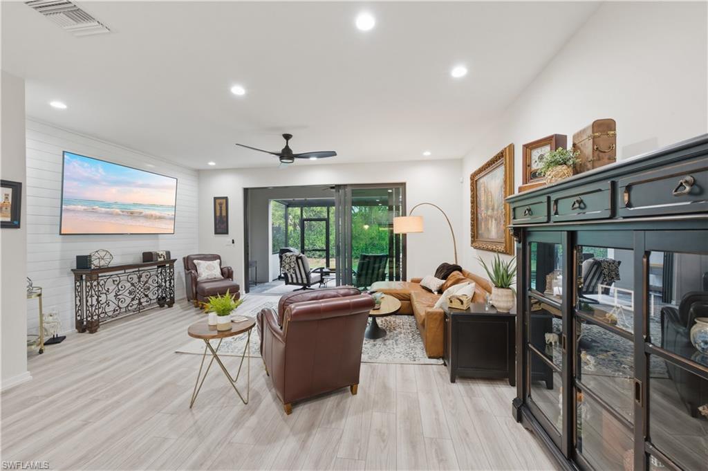 Living room with ceiling fan, light wood finished floors, recessed lighting, and wood walls