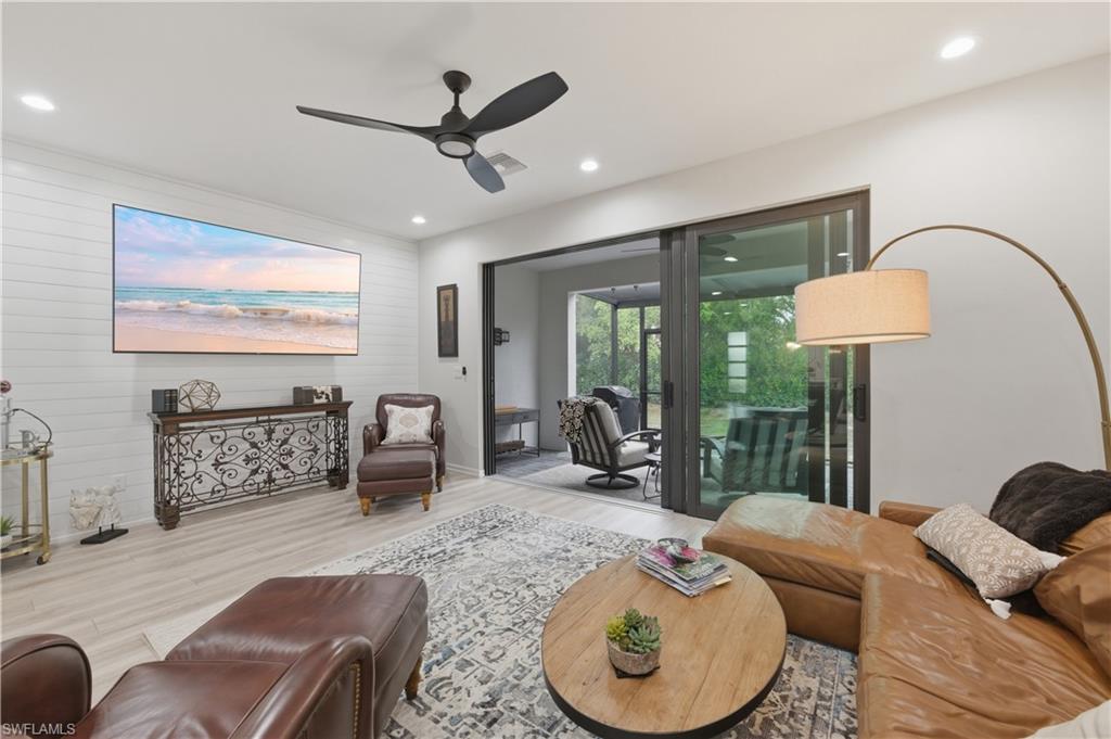 Living room with ceiling fan, wood finished floors, recessed lighting, and wooden walls