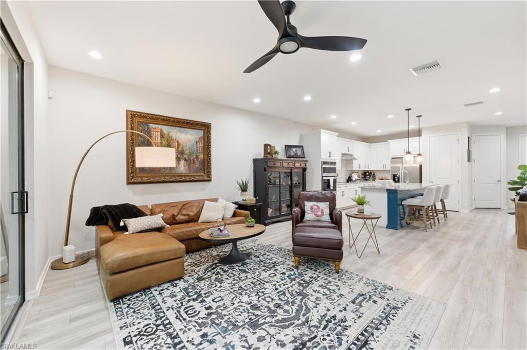 Living area with a ceiling fan, light wood-style flooring, and recessed lighting