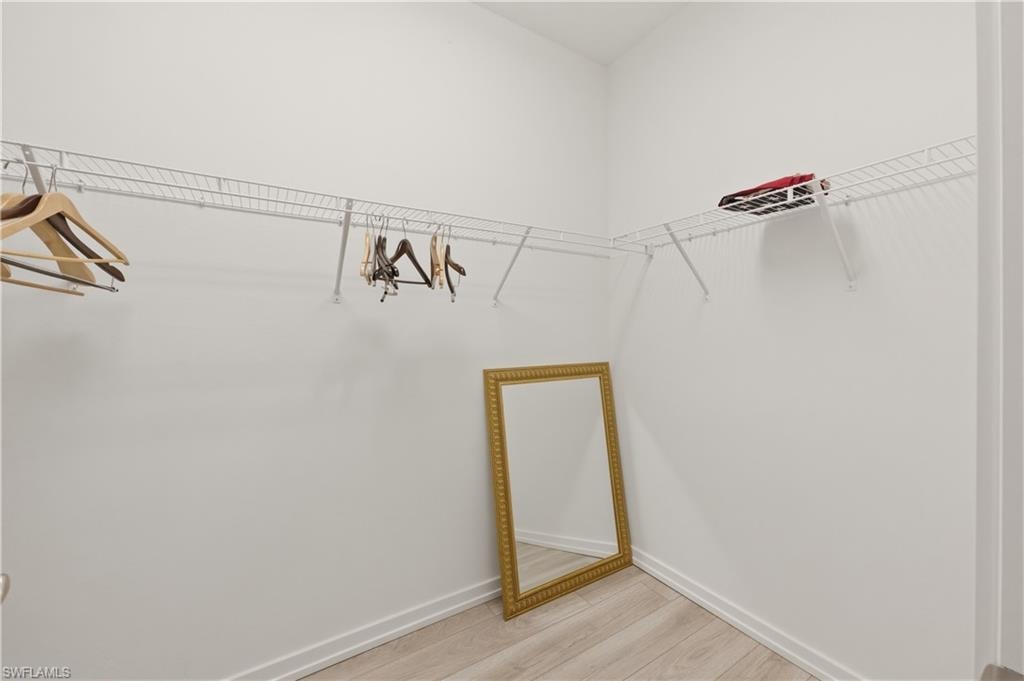 Walk in closet with light wood finished floors