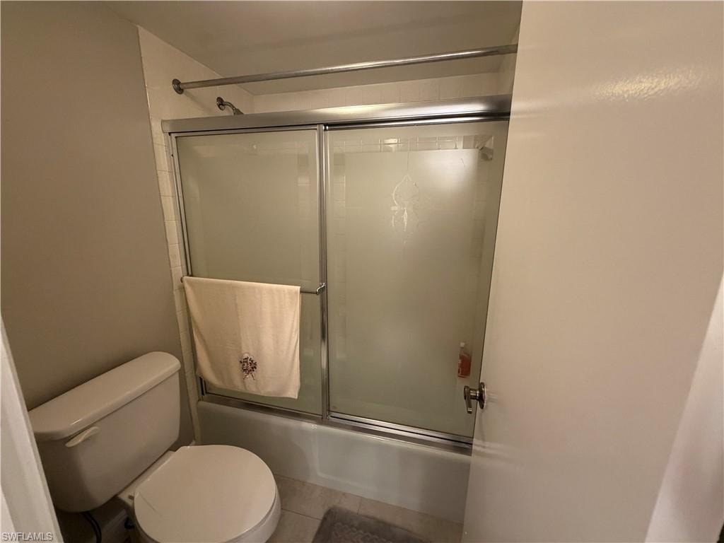 Bathroom featuring combined bath / shower with glass door and light tile patterned flooring
