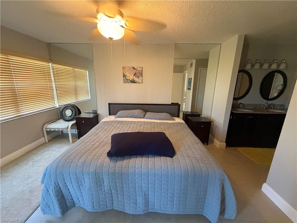 Bedroom featuring a textured ceiling, ceiling fan, and tile patterned floors